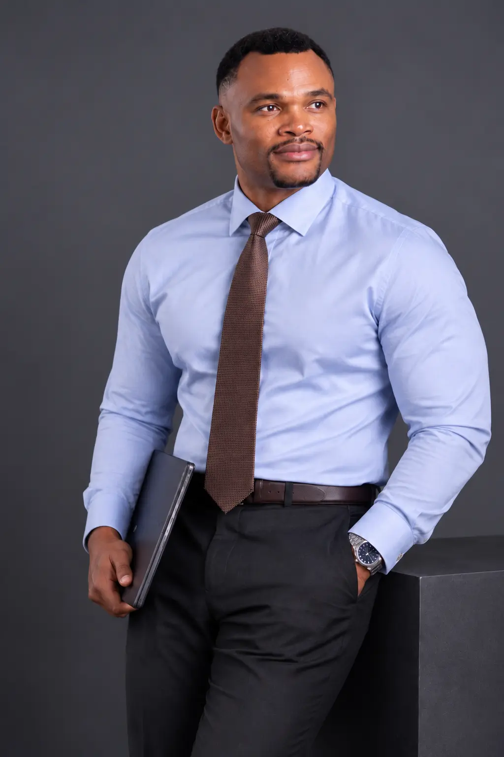 Godswill Ambrose in a black suit against a dark studio background