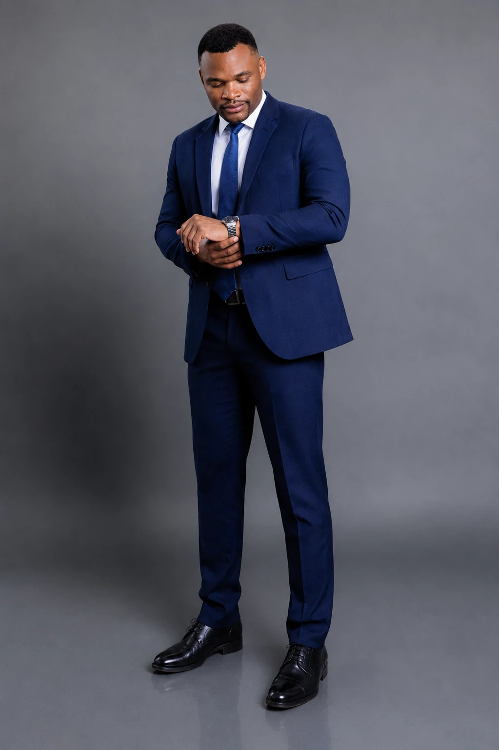 Full-length portrait of Godswill Ambrose in a navy suit