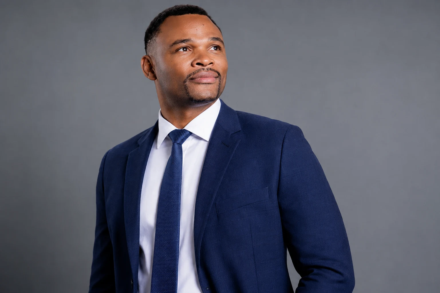 Godswill Ambrose in a navy suit looking to the side